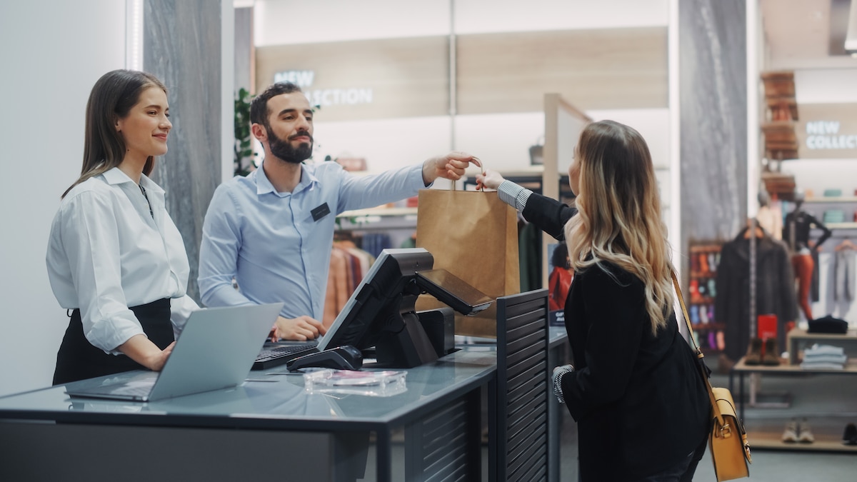 Femme payant à la caisse d'un magasin de vêtement.s