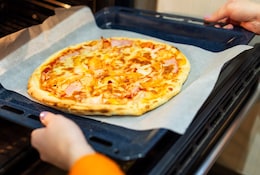 Femme sortant une pizza du four