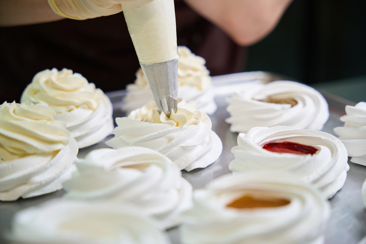 Personne appliquant de la crème sur un dessert.