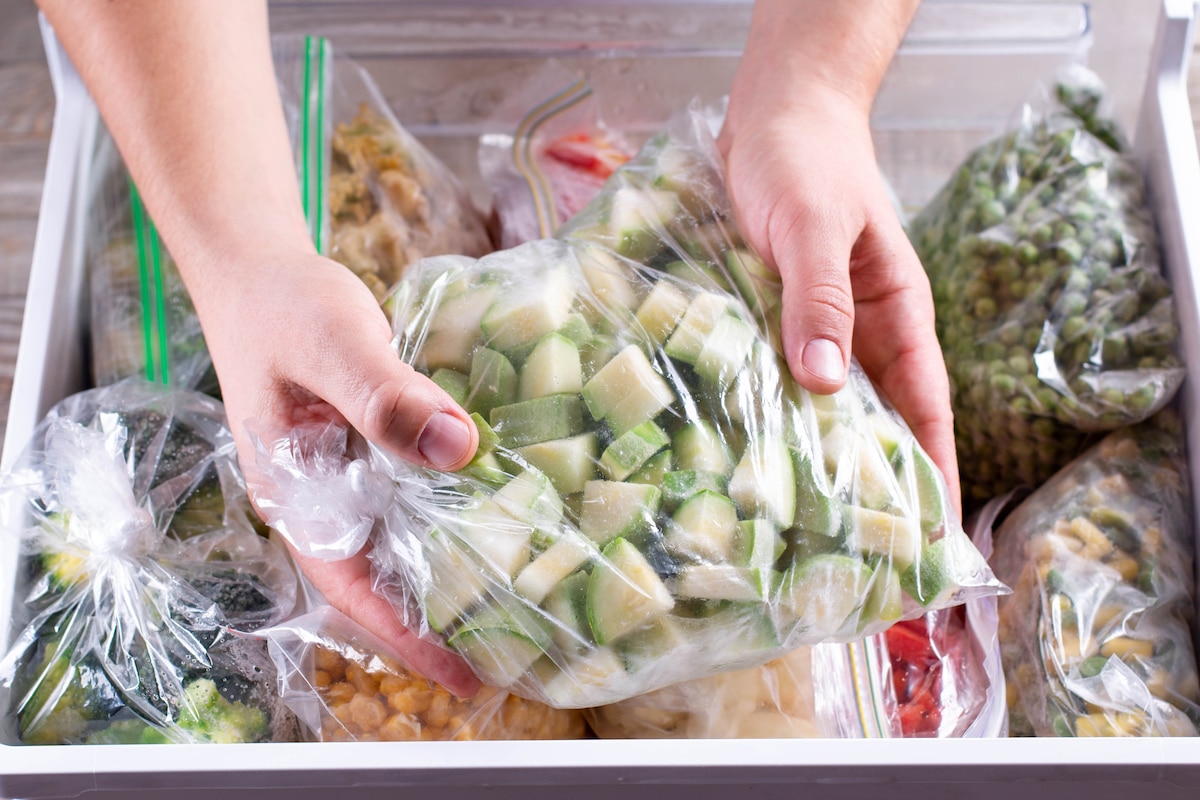 personne emballe courgettes coupées en cubes dans un sac plastique