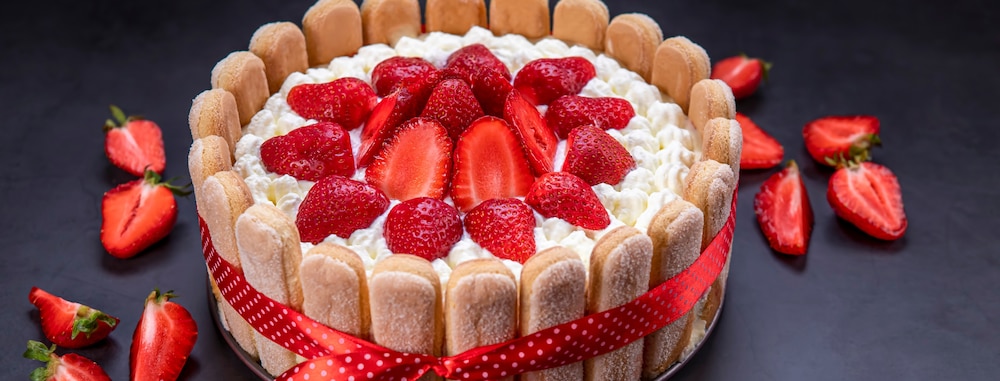 Charlotte aux fraises fait maison sur fond noir.