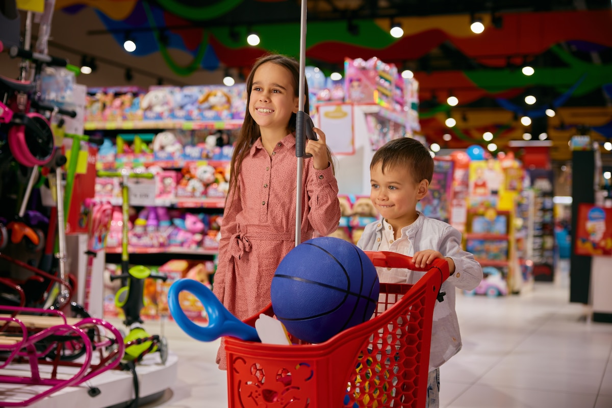 Une petite fille et son frère ravi de faire des courses dans une boutique de jouets.