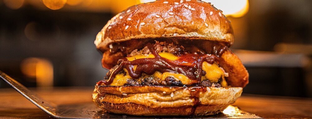 Gros plan sur un smash burger appétissant rempli de sauce bbq.