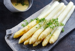 Asperges blanches glacées avec sauce hollandaise et cresson servie en gros plan sur un plateau design