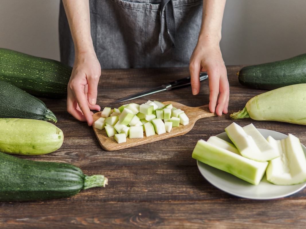 Personne découpant des courgettes en petits cubes