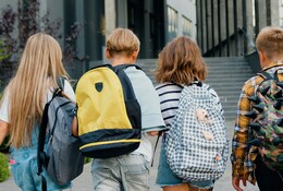 4 enfants de dos marchant avec leur cartables sur le dos