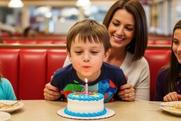 Jeune garçon fêtant son anniversaire avec sa famille dans restaurant de type américain.