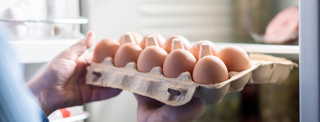 Femme mettant des oeufs dans un congélateur.