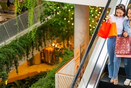 Deux femmes prenant l'escalator dans un grand magasin.
