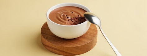Mousse au chocolat dans un petit bol blanc avec une petite cuillère à café.