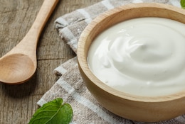 Pot de crème fraîche sur une table en bois.