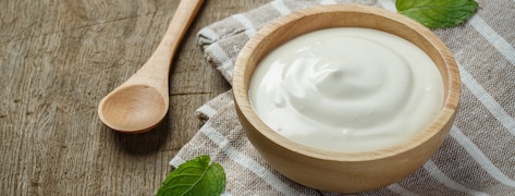 Pot de crème fraîche sur une table en bois.