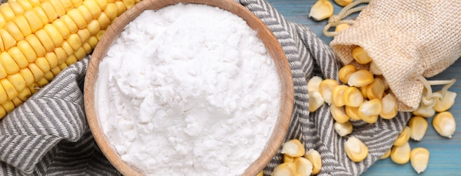 Bol rempli de maïzena entouré par du maïs.