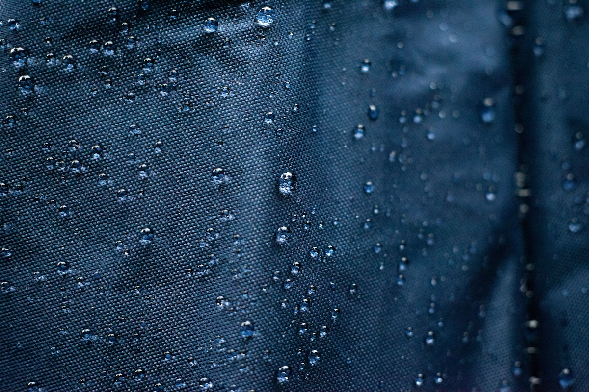 Gros plan sur des gouttes d'eau à la surface d'un tissu bleu.
